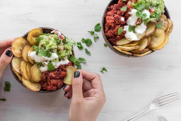 hand holding plant-based food bowl mix of avocado salsa and potato