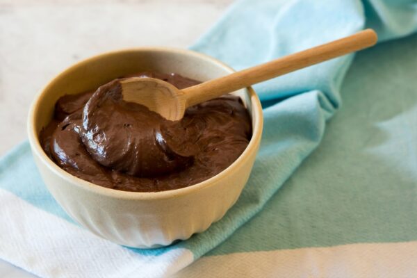 chocolate vegan mousse on wooden bowl with wooden spoon on top
