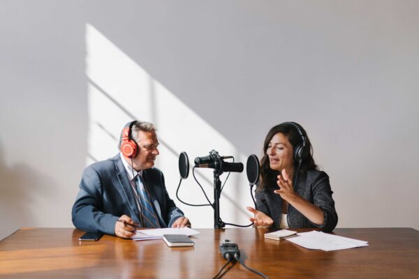 two people sitting in table to talk in a podcast