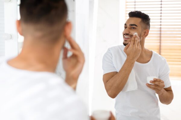 a man in front of the mirror applying men's grooming product