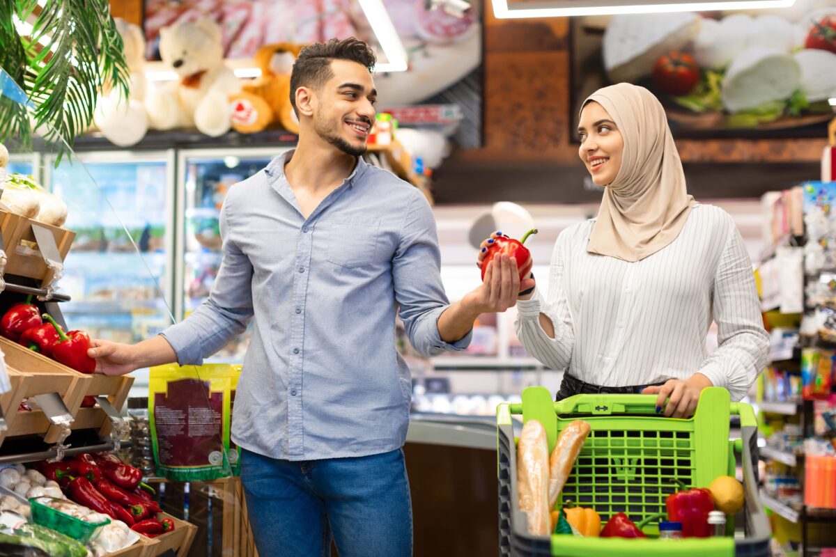 A man and a woman wearing hijabs are shopping for fruit at a supermarket during the month of Ramadan.